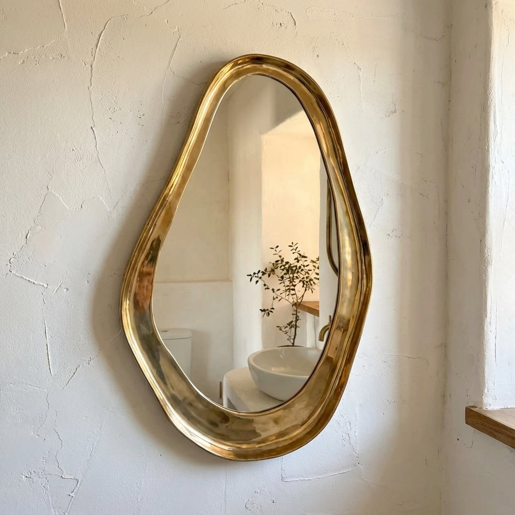 Unlacquered brass organic wall mirror with sculptural handmade frame in minimalist bathroom interior