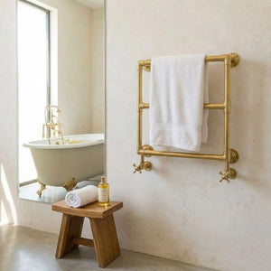 Luxury unlacquered brass heated towel warmer installed beside a freestanding bathtub