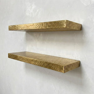 Handmade hammered brass floating shelves mounted on plaster wall, minimalist styling