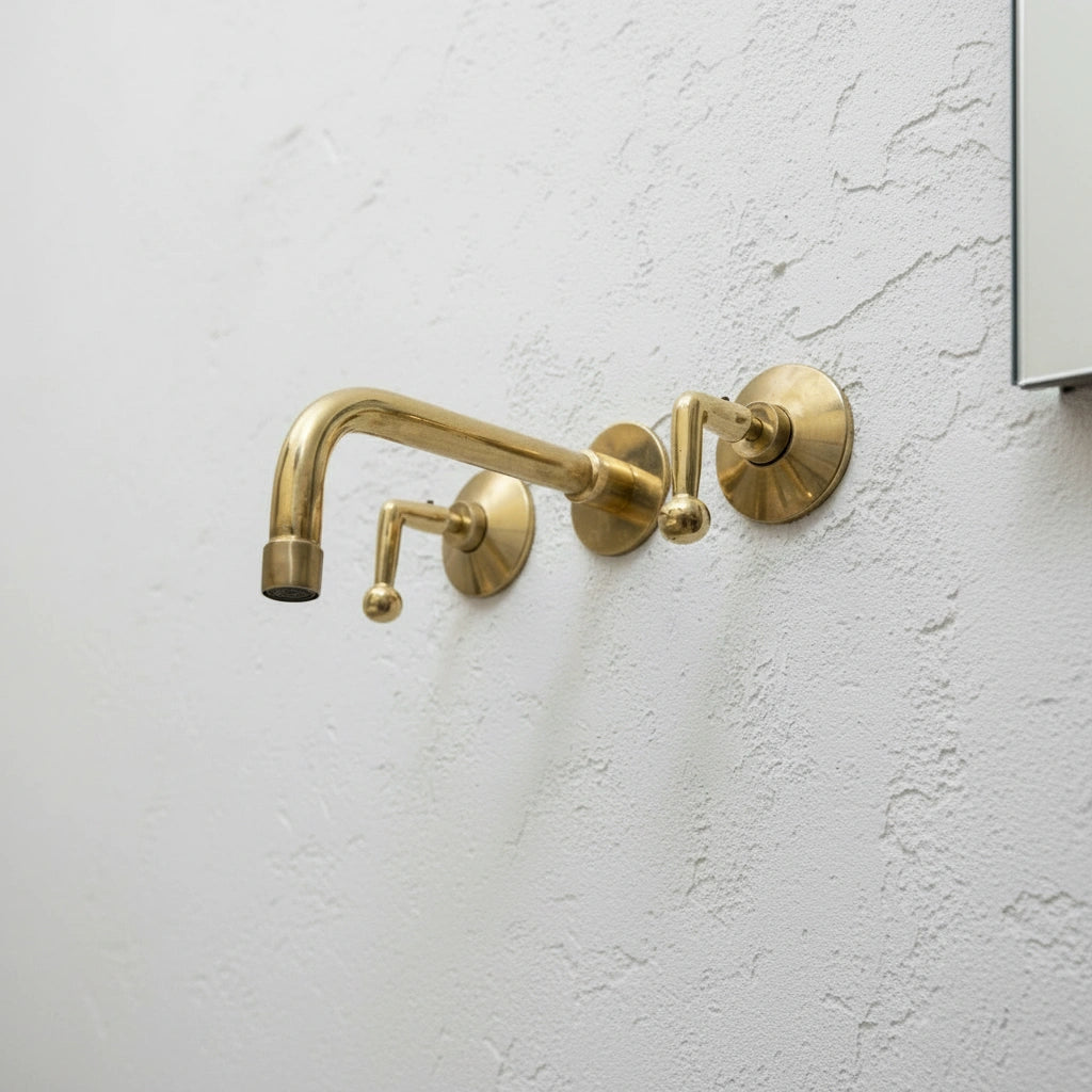Brass wall-mounted faucet on a light gray wall