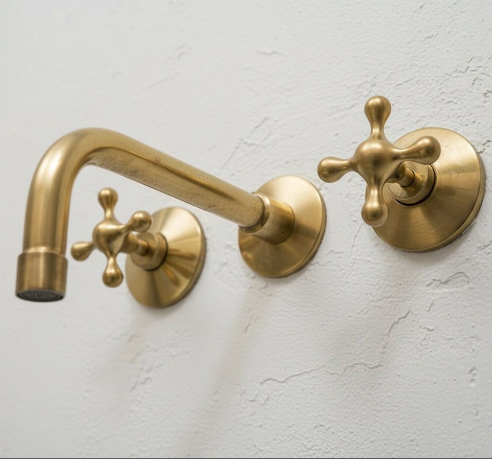 Gold wall-mounted faucet set on a light gray wall