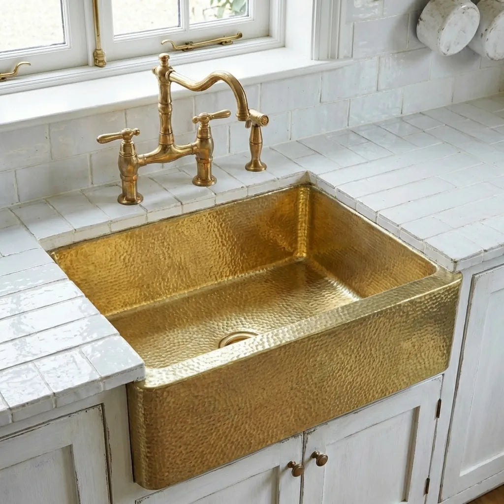 Unlacquered brass farmhouse kitchen sink with textured hammered finish and deck-mounted faucets