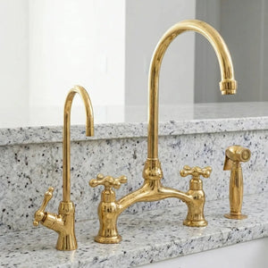 Vintage style brass bridge faucet with handheld sprayer beside farmhouse sink

