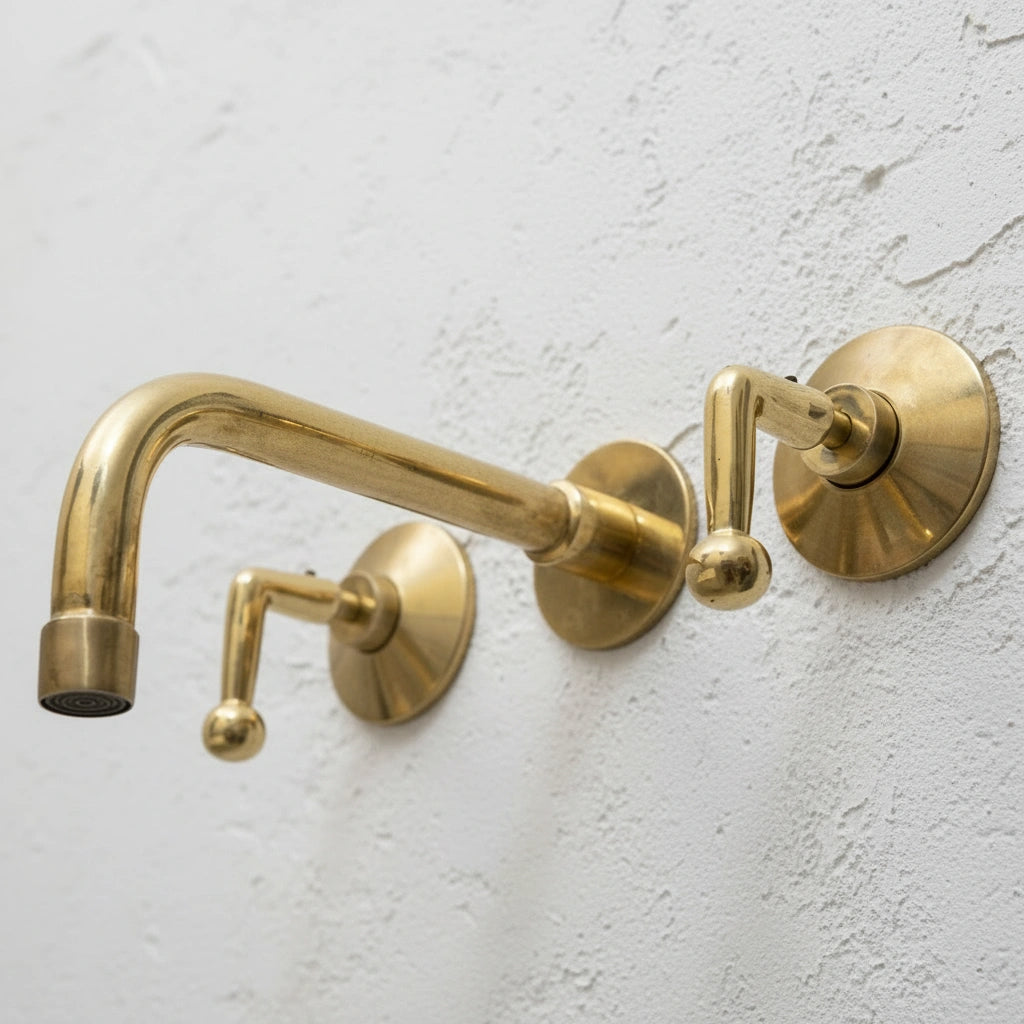 Gold wall-mounted faucet set against a light gray wall