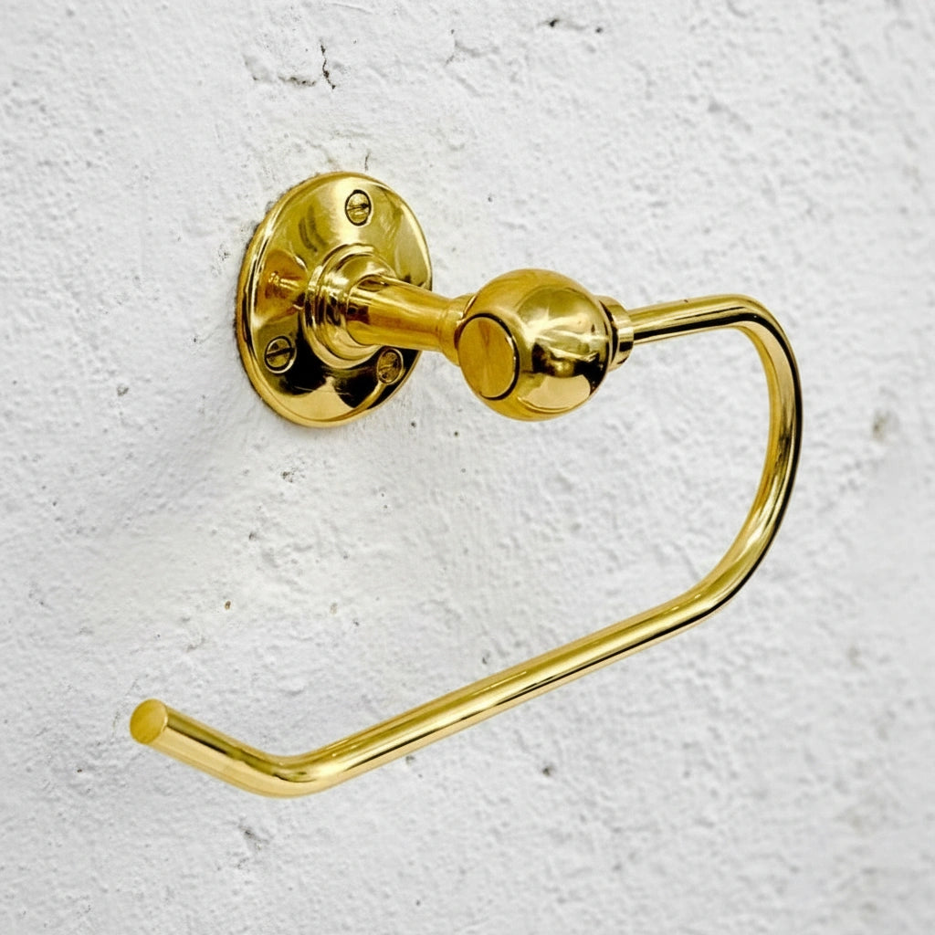 unlacquered brass toilet paper holder on a textured white wall
