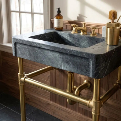 Dark gray marble console sink on a solid brass washstand frame with front towel rail