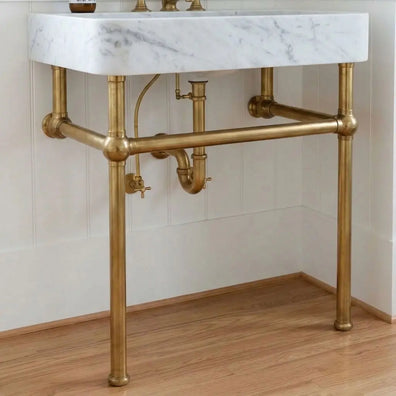 Solid unlacquered brass console sink legs supporting a white marble basin, front view