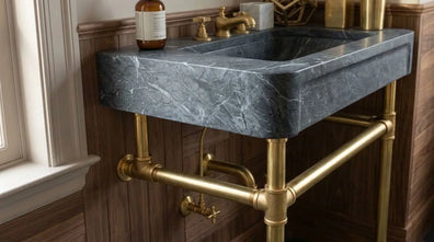 Handmade stone console sink supported by unlacquered brass bathroom legs, angled view