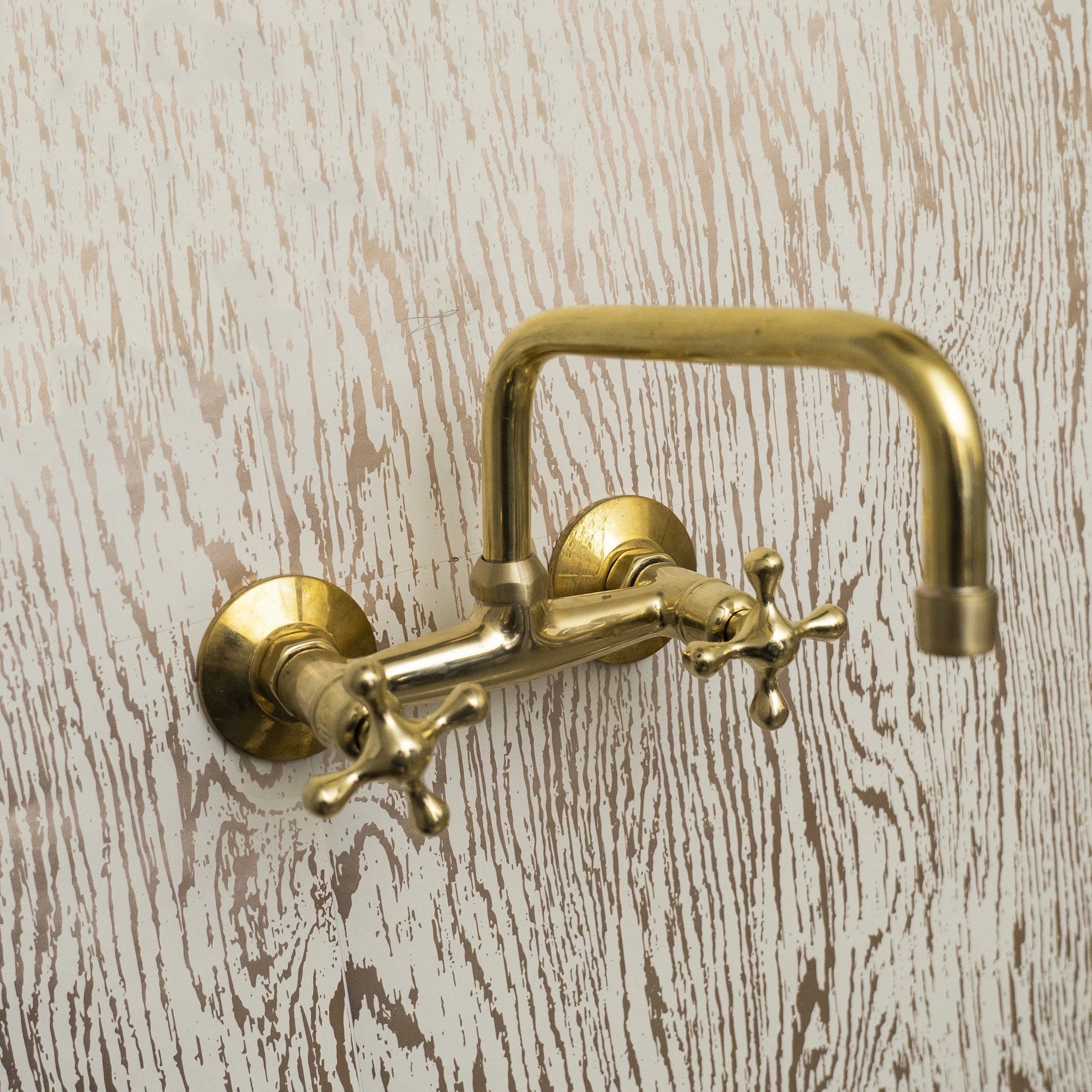 Gold wall-mounted faucet on a wooden background