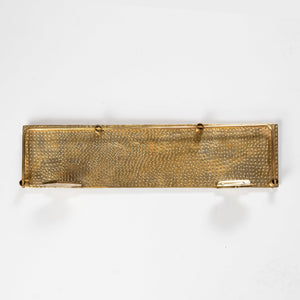 Underside view of a handmade hammered brass floating wall shelf with guard rail