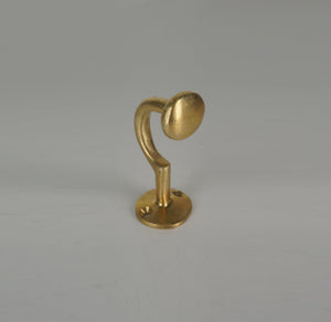 Front angled view of a handmade brass coat hook with rounded end and circular base