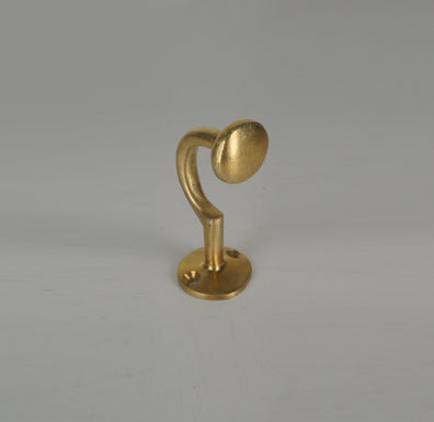 Front angled view of a handmade brass coat hook with rounded end and circular base