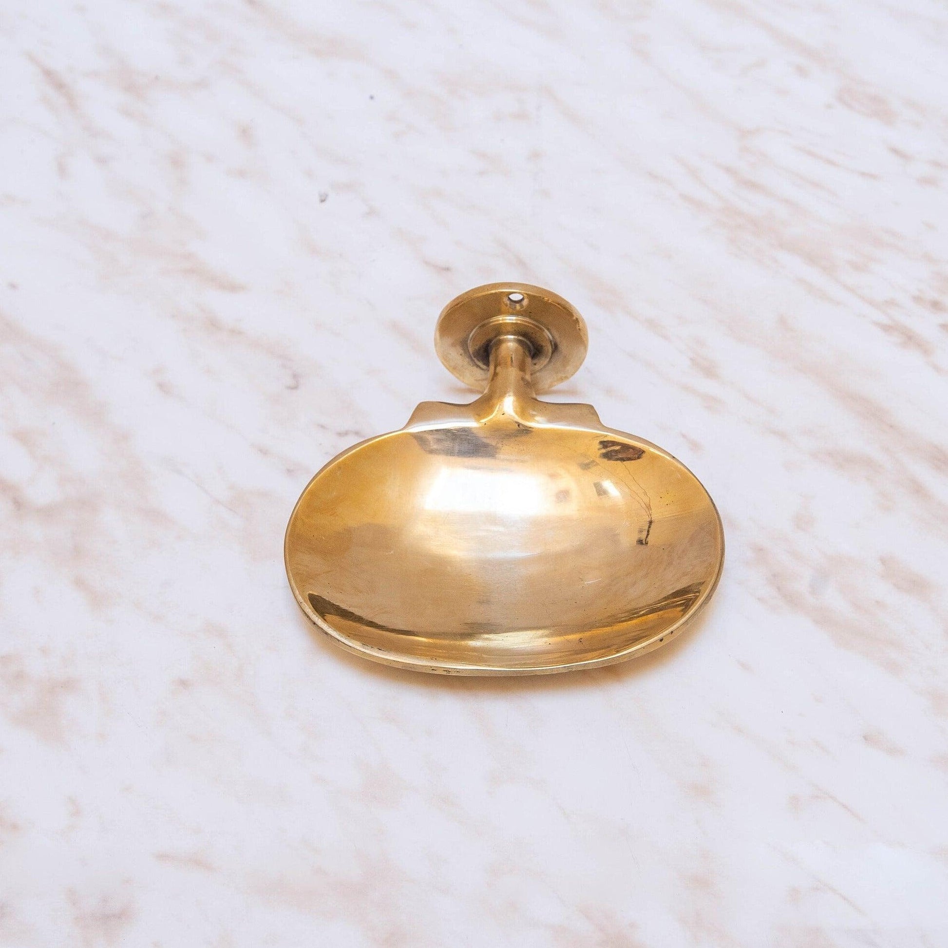 Front view of a handmade brass wall-mounted oval soap dish