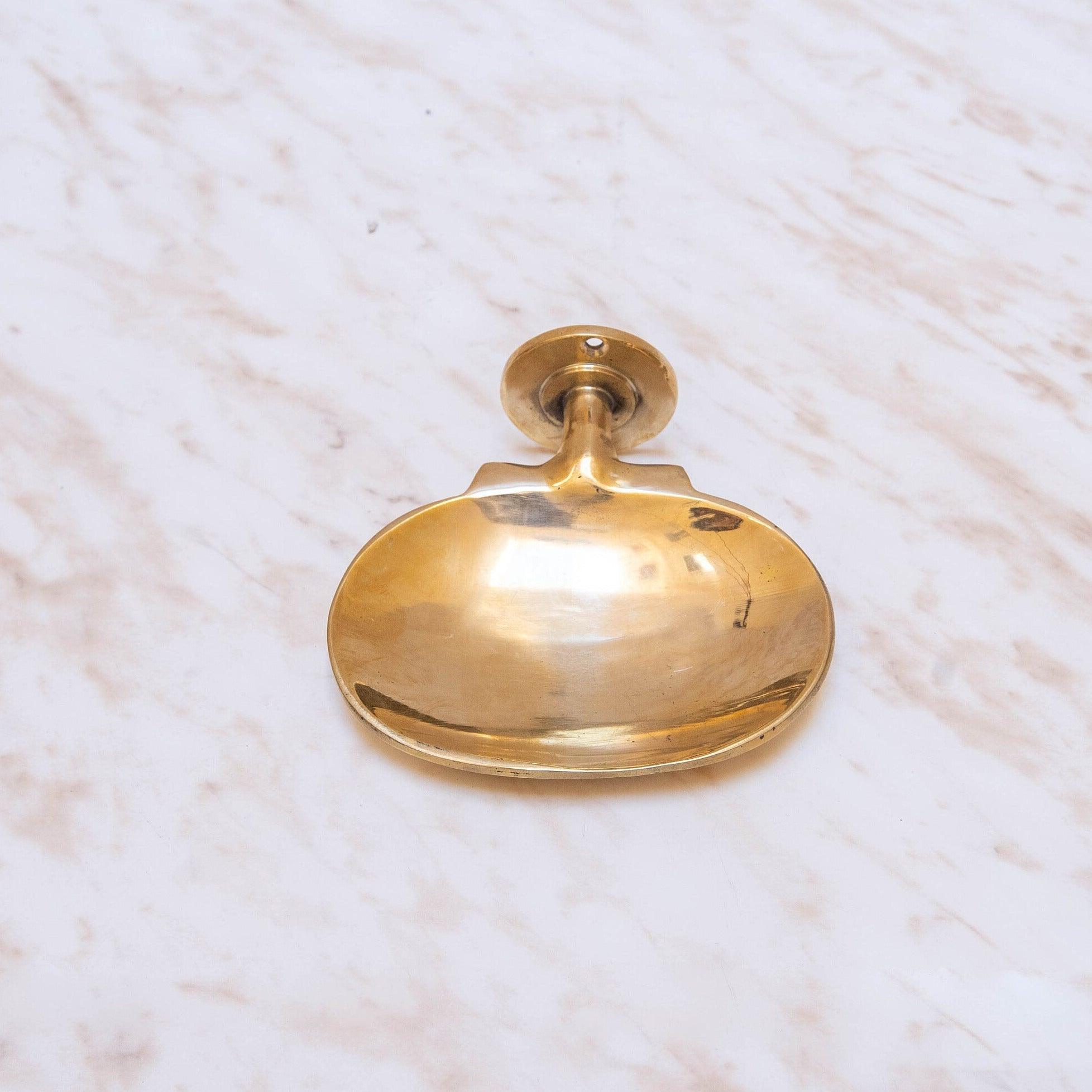 Front view of a handmade brass wall-mounted oval soap dish