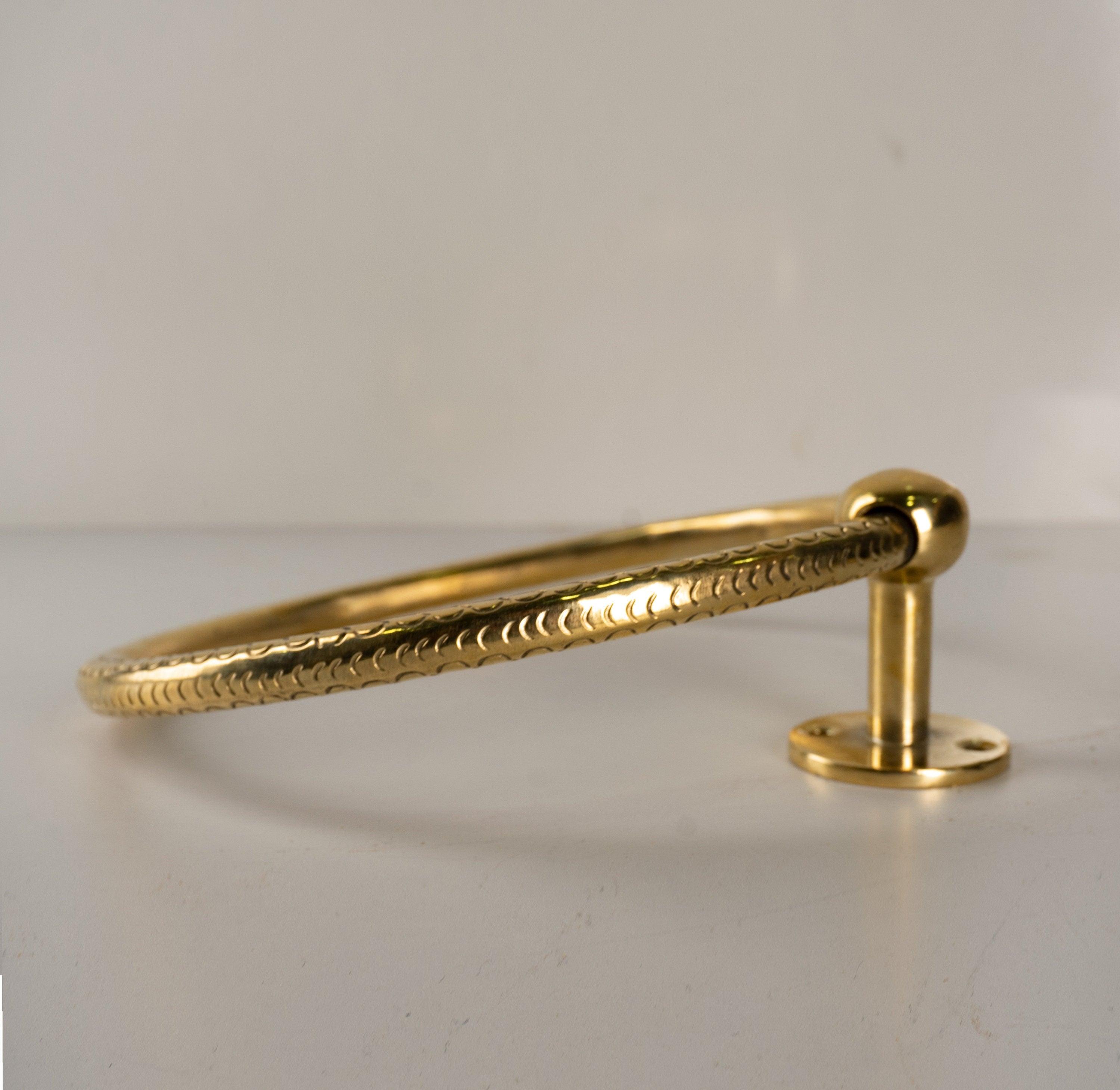 Angled view of a handmade solid brass towel ring and wall mounting base