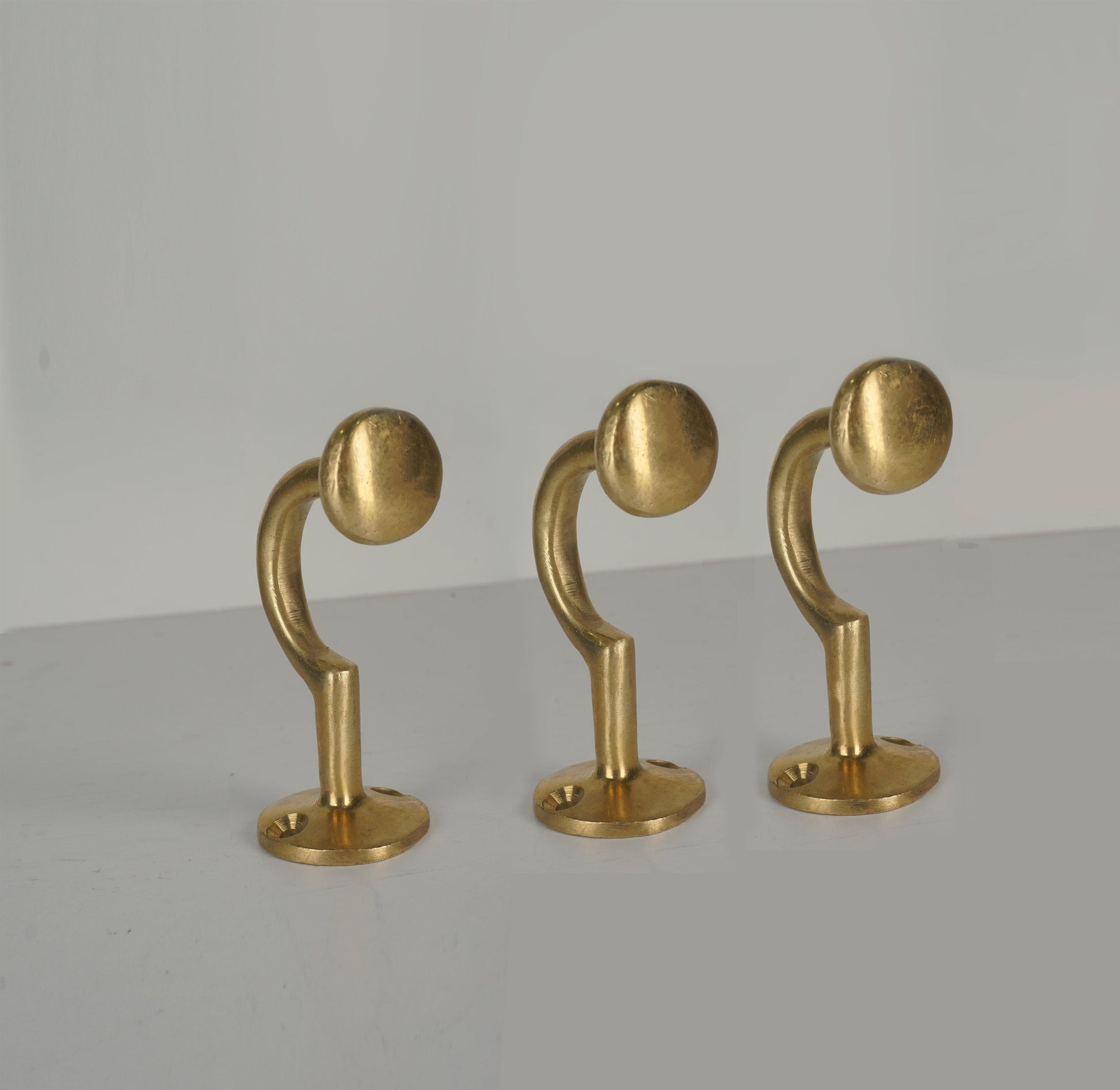 Set of three vintage unlacquered brass wall coat hooks with round ends