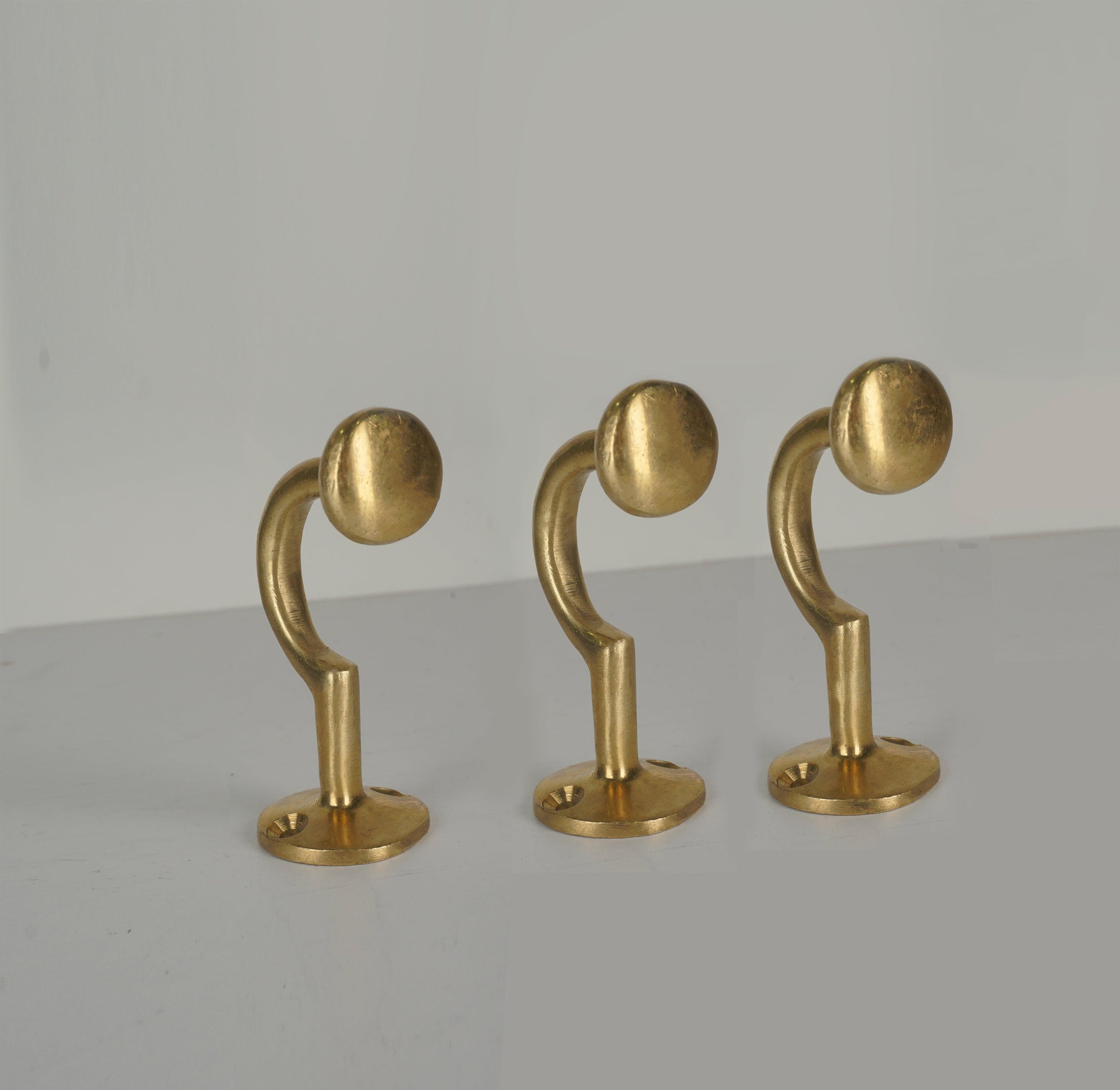 Set of three vintage unlacquered brass wall coat hooks with round ends