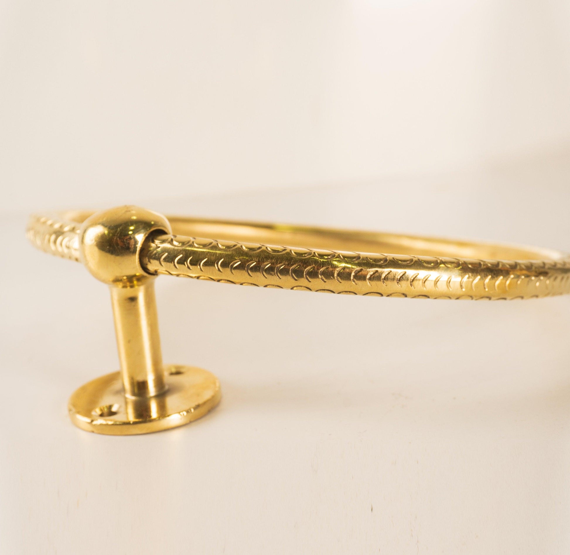 Side detail of a solid brass bathroom towel ring with round mounting plate