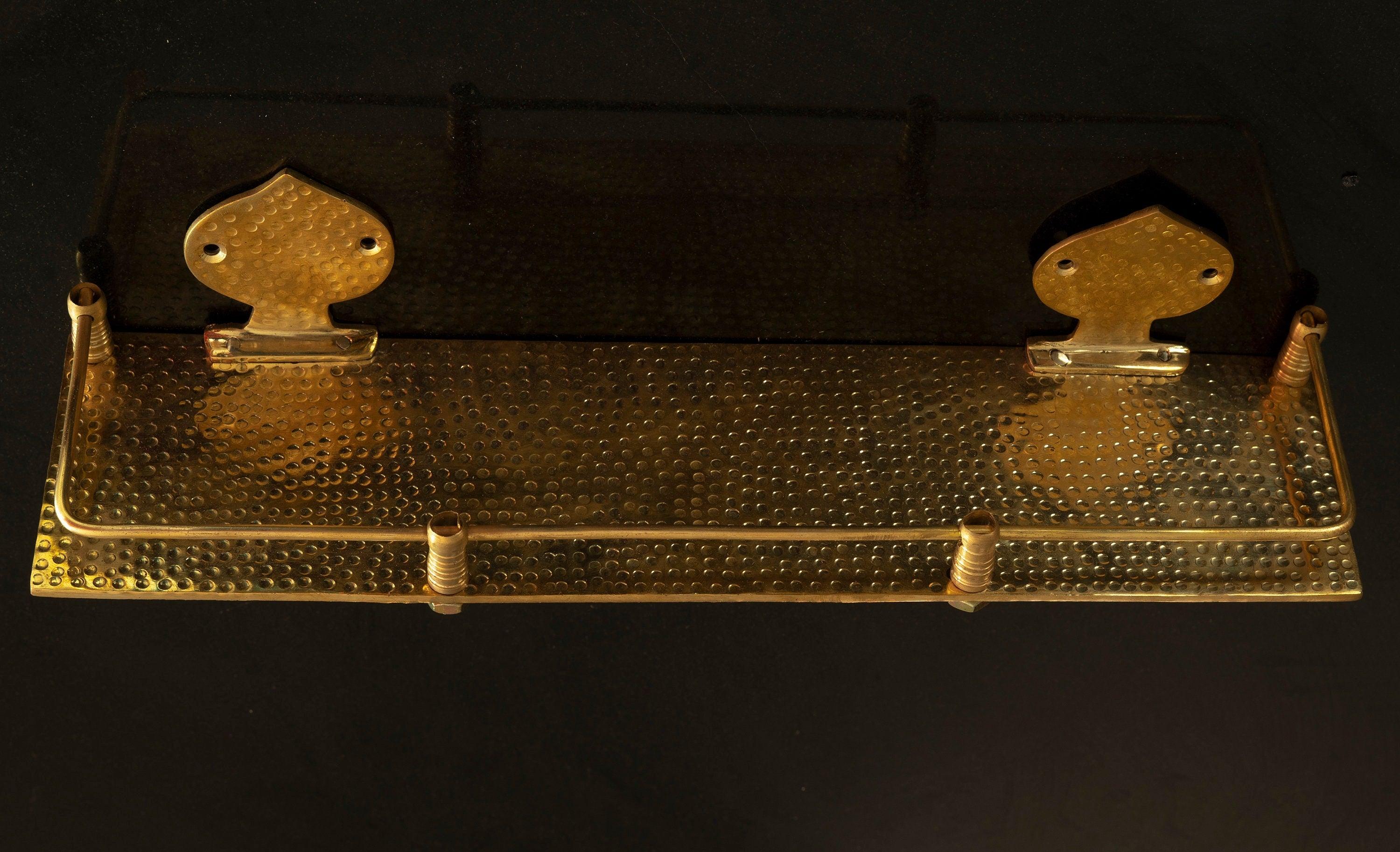 Solid brass hammered floating bathroom shelf with front rail on a black background
