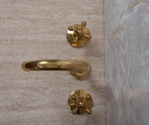 Top view of a three-hole unlacquered brass widespread bathroom faucet with cross handles