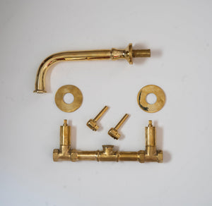 Unlacquered brass wall-mounted bathroom faucet parts with curved spout and cross handles