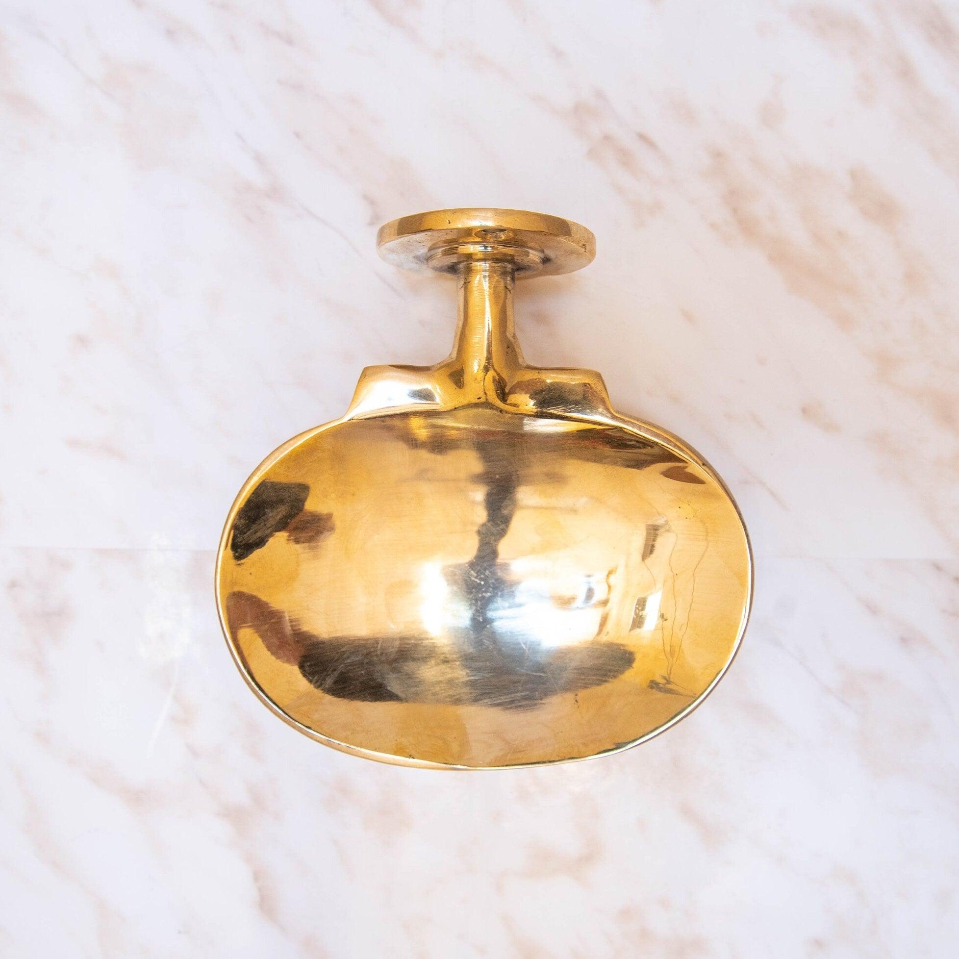 Top view of an unlacquered brass wall-mounted oval soap dish with round mounting plate