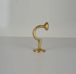 Profile view of a vintage unlacquered brass wall hook with curved stem