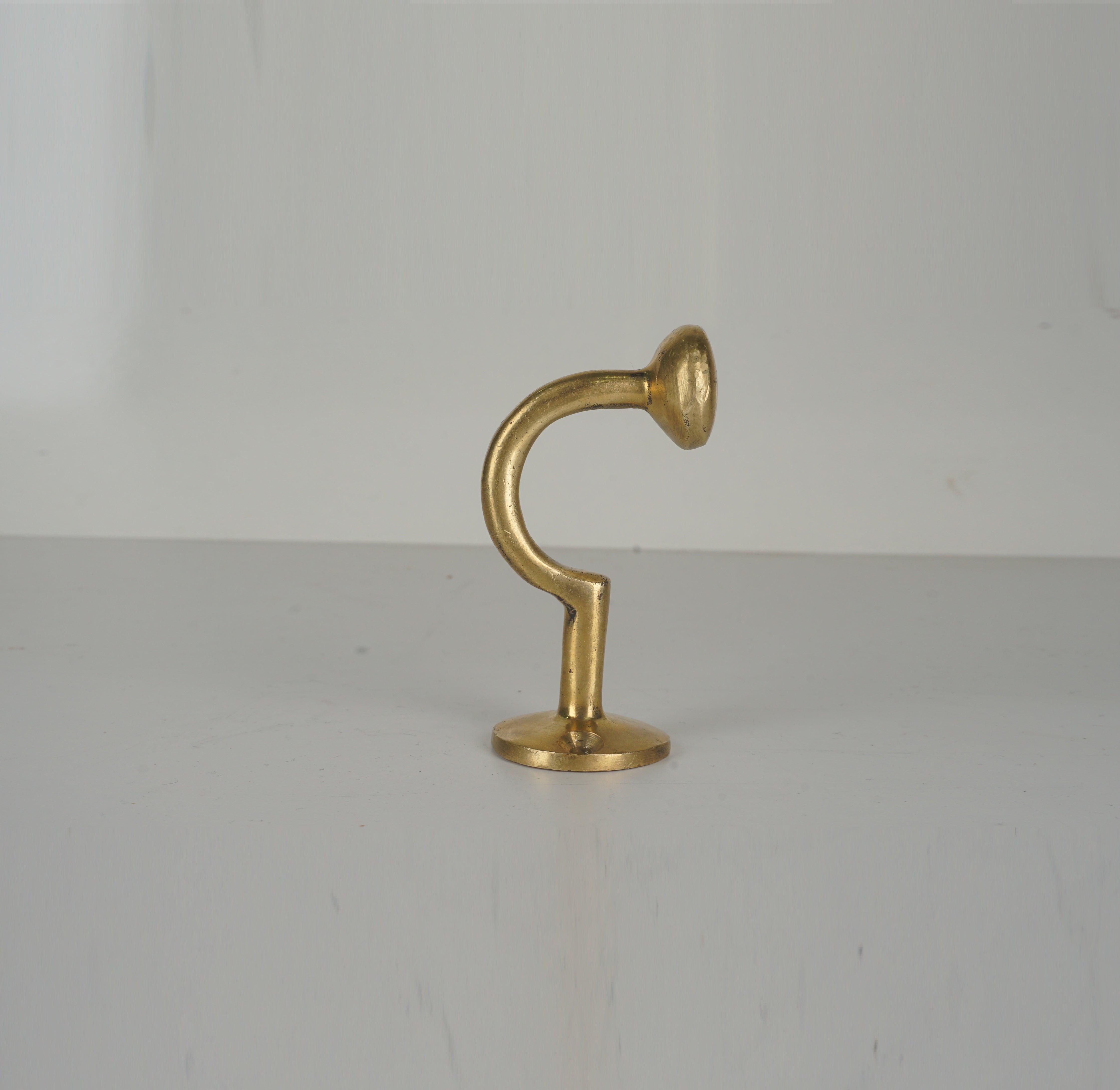 Profile view of a vintage unlacquered brass wall hook with curved stem